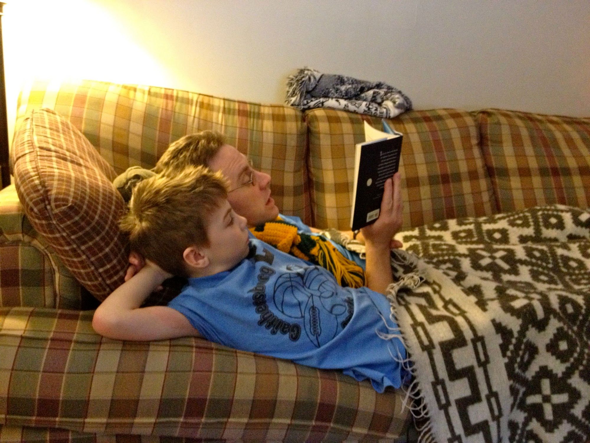 Daddy and Boogie snuggling on the couch reading the first book in the Rise of the Guardians series